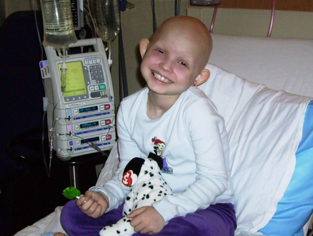 Gaby smiling while sitting on a hospital bed during treatment